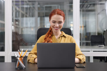 Junge Assistentin arbeitet an Laptop in Büro
